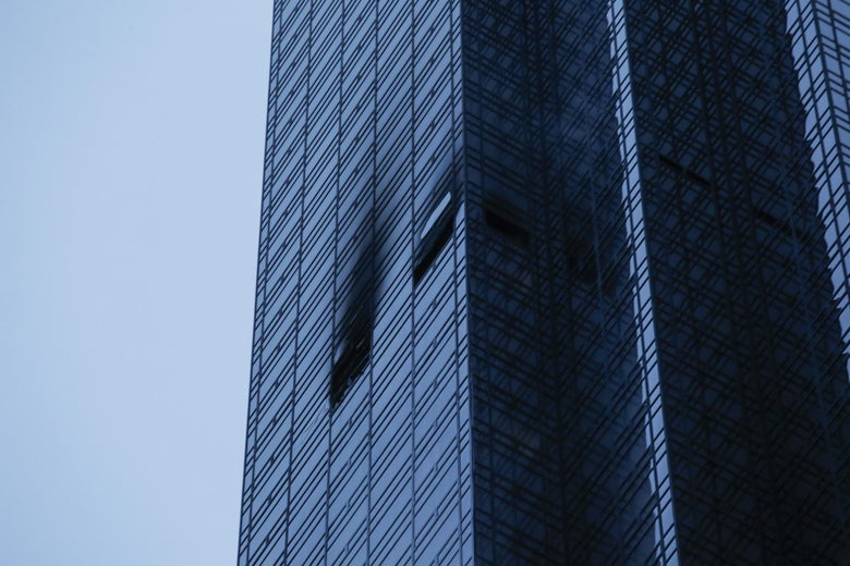 On the side of Trump Tower, two windows are burnt and broken.